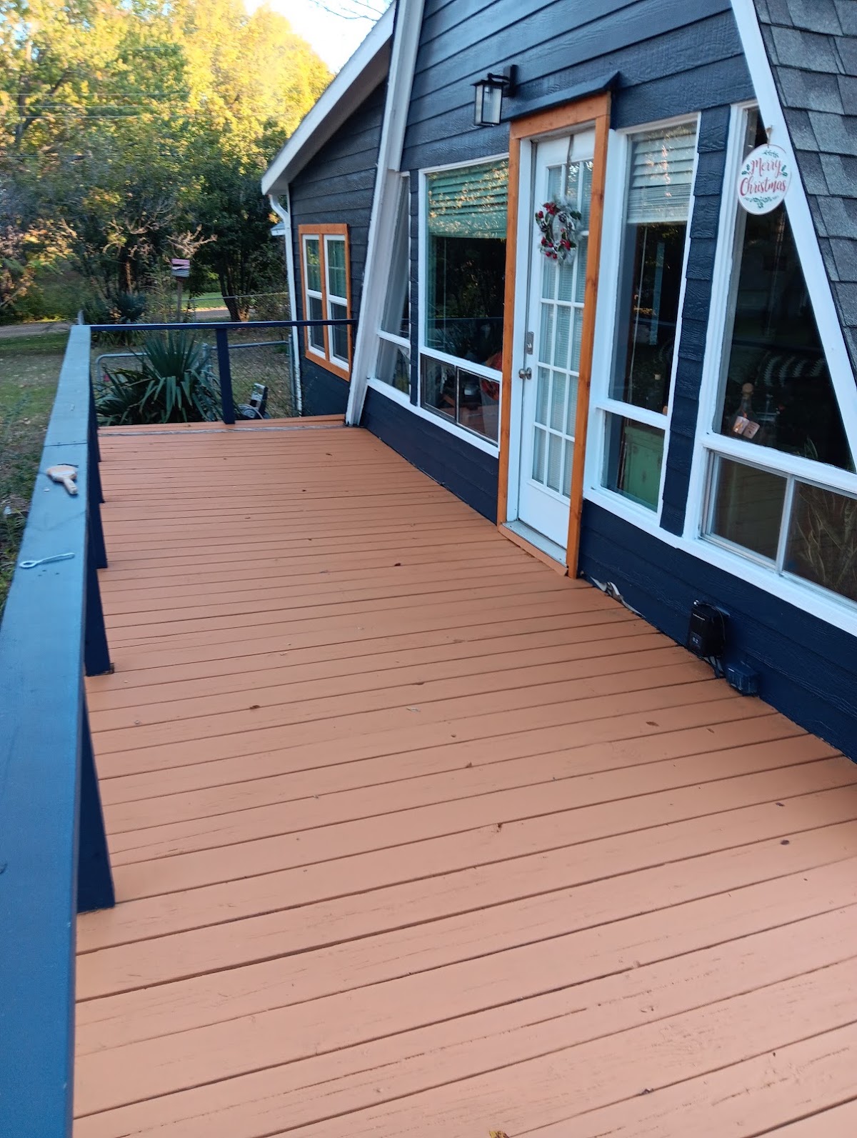 Navy blue house exterior with white window trim and a freshly painted deck